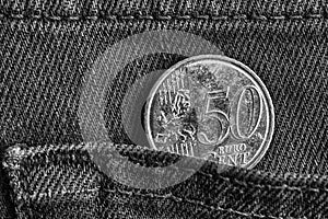 Euro coin with a denomination of 50 euro cents in the pocket of denim jeans, monochrome shot