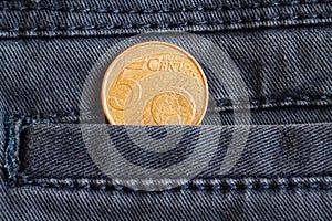 Euro coin with a denomination of 5 euro cents in the pocket of worn gray denim jeans