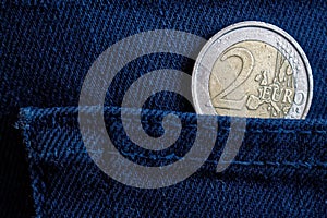 Euro coin with a denomination of 2 euro in the pocket of worn dark blue denim jeans