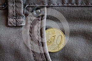 Euro coin with a denomination of ten euro cent in the pocket of worn gray denim jeans