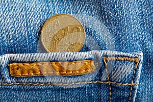 Euro coin with a denomination of ten euro cent in the pocket of worn blue denim jeans with orange laces