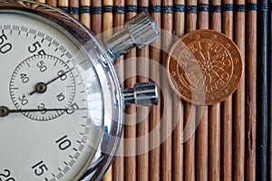 Euro coin with a denomination of two euro cents and stopwatch on wooden table - back side