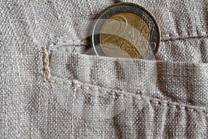 Euro coin with a denomination of 2 euros in the pocket of worn linen pants photo