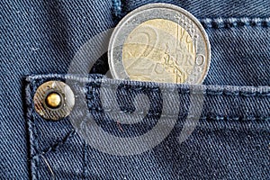 Euro coin with a denomination of two euro in the pocket of blue denim jeans