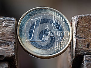 A Euro coin held in a metal grip.