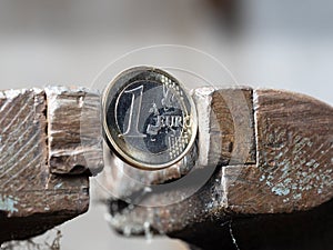A Euro coin held in a metal grip. Concept of financial problems.