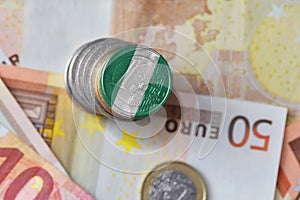 Euro coin with national flag of nigeria on the euro money banknotes background.