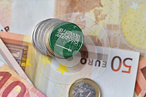 Euro coin with national flag of saudi arabia on the euro money banknotes background.