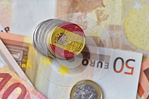 Euro coin with national flag of spain on the euro money banknotes background