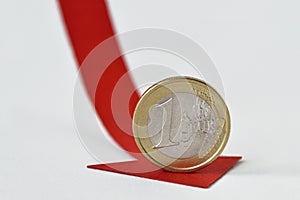 Euro coin on red decreasing arrow - Concept of decrease in euro value and loss of money