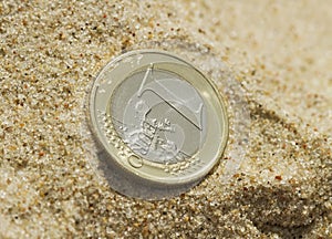 Euro coin on sand.