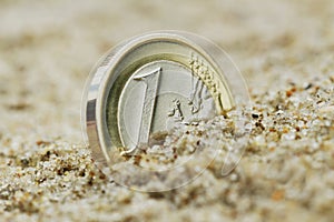 Euro coin on sand.