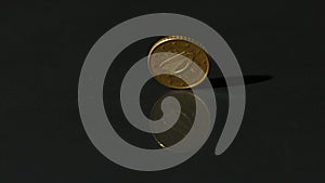 Euro coin spinning on black surface