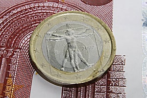 Euro coin standing on paper money