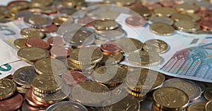Euro coins covering different Banknotes from five to twenty Euros. Bunch of coins and European Currency