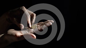 Euro coins falling into the dirty hands of a man, a worker recounts money on a black background in the darkness