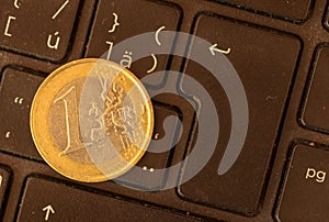 Euro coins lie on a laptop keyboard. Close up, space for text. C