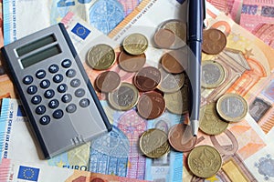 Euro coins, notes, calculator and pen