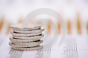 Euro coins stacked over data of exchange market