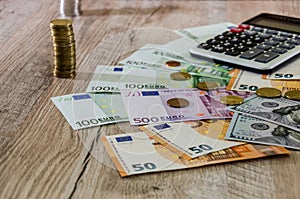 Euro, dollars, cents and calculator spread out on a wooden background