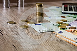 Euro, dollars, cents and calculator spread out on a wooden background