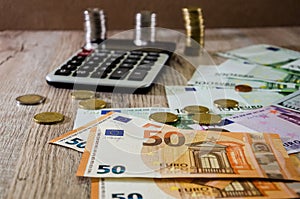 Euro, dollars, cents and calculator spread out on a wooden background