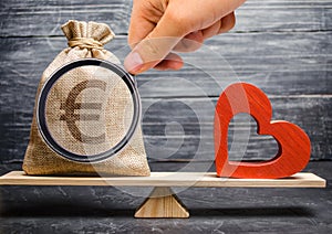 Euro money bag and red wooden heart on the scales. Money versus love concept. Passion versus profit. Family or career choice.