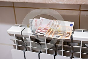 Euro money banknotes on heating radiator battery with temperature regulator at home