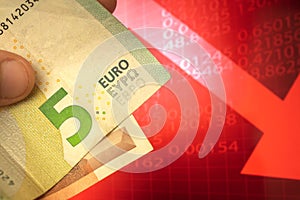 Euro money descending concept, euro banknotes in hand, currency going down background of red arrow, finance and business