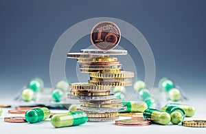 Euro money and medicaments. Euro coins and pills. Coins stacked on each other in different positions and freely pills around photo