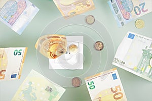 Euro money paper banknotes fall into a white electric socket on light green background. Increasing cost of electricity