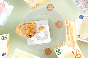 Euro money paper banknotes fall into a white electric socket on light green background. Increasing cost of electricity