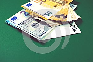 Euro notes and dollar bills on green background