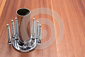 Euro screws, dowels, ties, chrome-plated pipe and console are laid out on a wooden panel