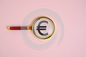 Euro symbol under magnifying glass, on pink background