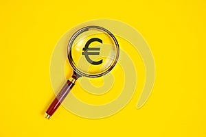 Euro symbol under magnifying glass, on yellow background