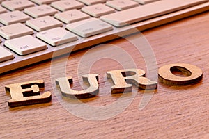 euro writing on wooden table with white keyboard in the background