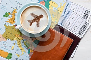 Europe map, passports, boarding pass and cup of coffee (airplane made of cinnamon)