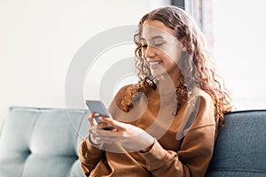 European adolescent girl browsing internet on phone in cozy home