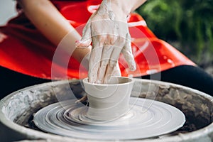 European artist girl making clay dishes on potter wheel, happy and smiling. Concept of love for work, craft