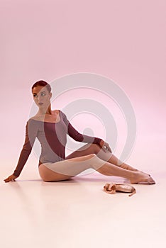 European ballerina sit on floor and look away