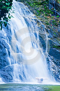 European bare-chested man relaxing under refreshing freshwater of waterfall