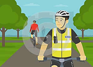 European bicycle patrol. Police officer riding bike on bike path in city park.