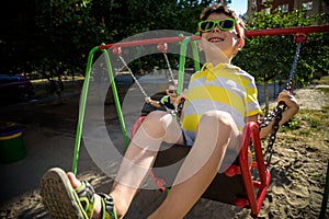 European boy on chain swing. Summer leisure time concept