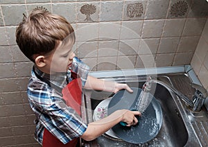 European boy washes dishes at home