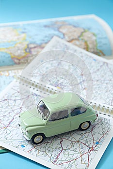 European classic car in miniature driving through a road map. Space for text