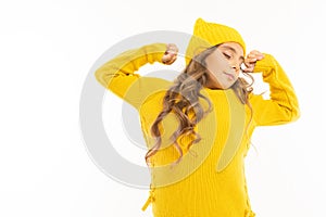 European cute girl in yellow clothes wakes up and stretches on a white background with copyspace