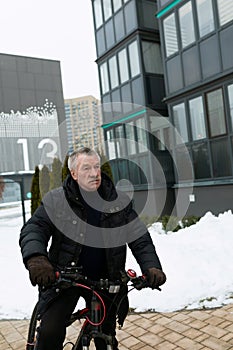 European elderly man leading a healthy lifestyle and riding a bicycle in winter
