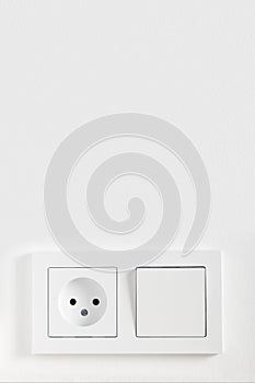 European electric light switch and socket on the painted white wall