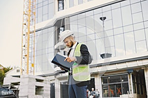 European engineer in helmet looking at paper plan